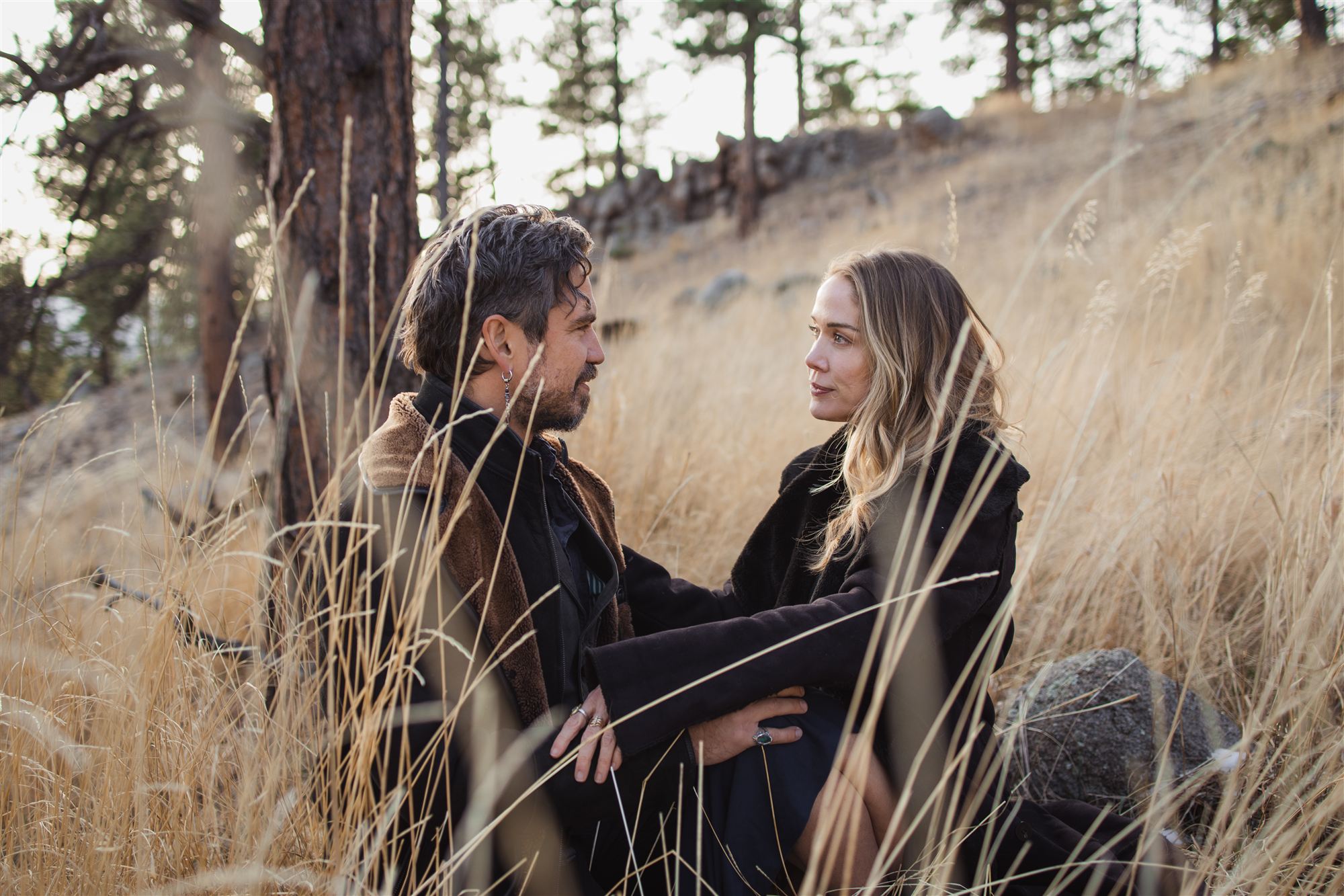Jen and Atilla seated in tall golden grass, facing each other